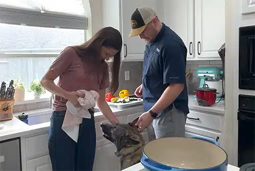 Beverly and Michael pause in their kitchen to pet one of their dogs