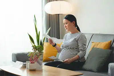 pregnant woman looking over her finances with worried expression on her face